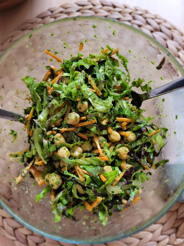 Ensalada de garbanzos, zanahoria rallada y hojas verdes en un bol de cristal